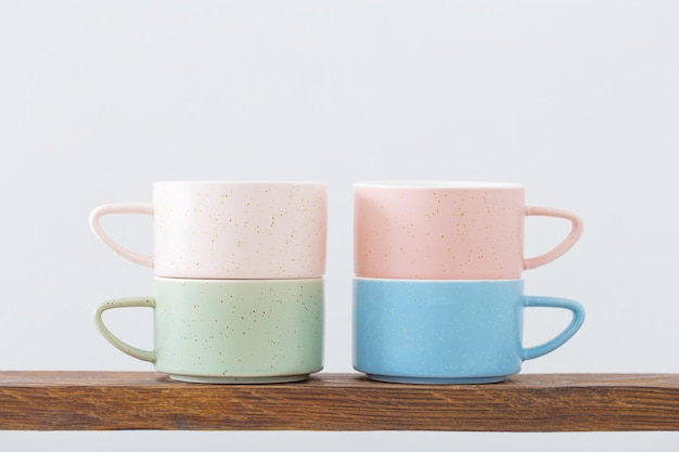 Colorful cups on  wooden shelf on  white background