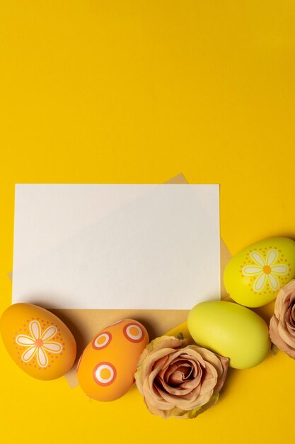 Colorful decorated easter eggs with blank card on pastel orange background creative design