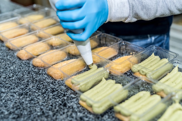 Colorful and delicious pistachio dessert in plastic package on table in factory. Food industrial manufacturing