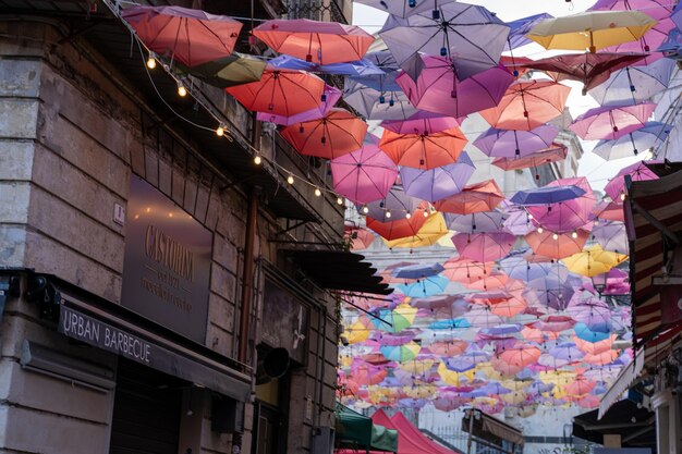 A colorful display of umbrellas hangs above a building