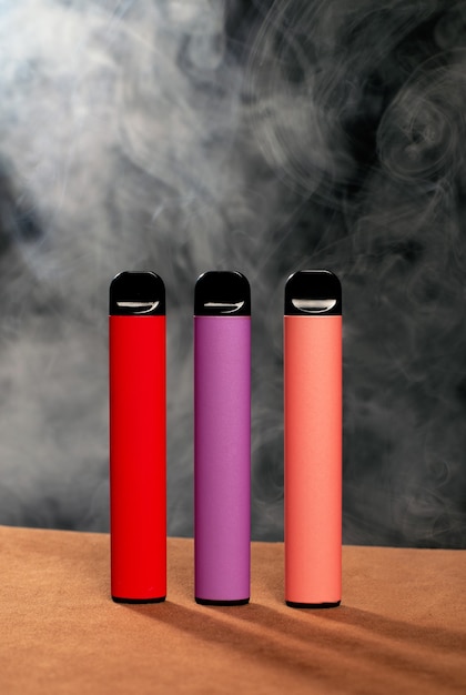 연기와 함께 검은 배경에 다채로운 일회용 전자 담배