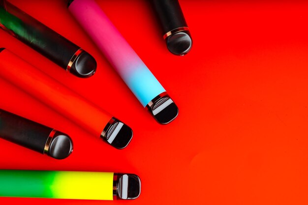 Photo colorful disposable electronic cigarettes on red background