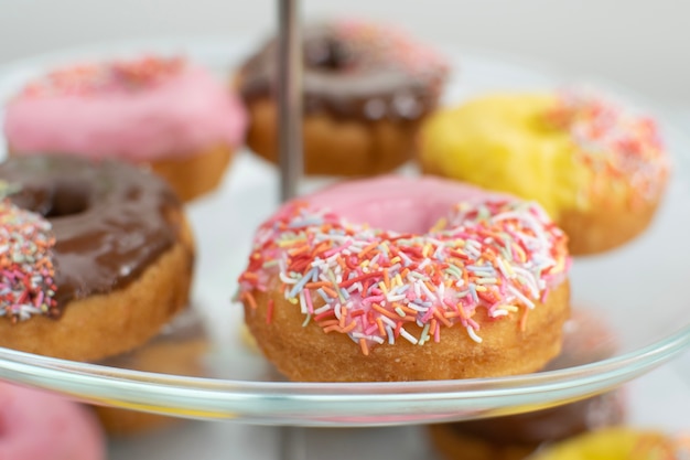 Photo colorful donuts on the glass stand for party