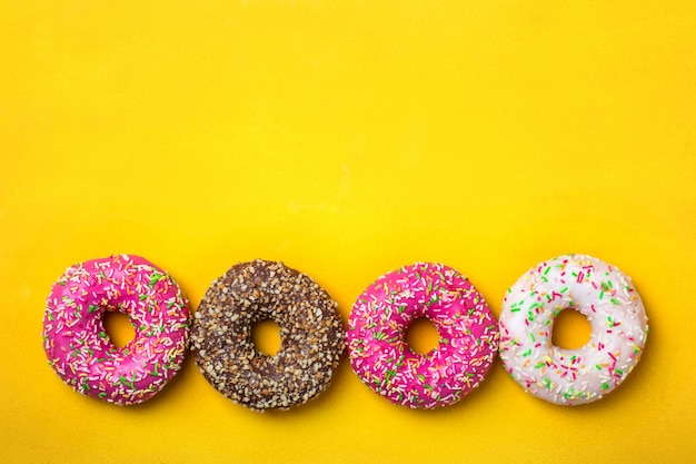 Colorful donuts on yellow background