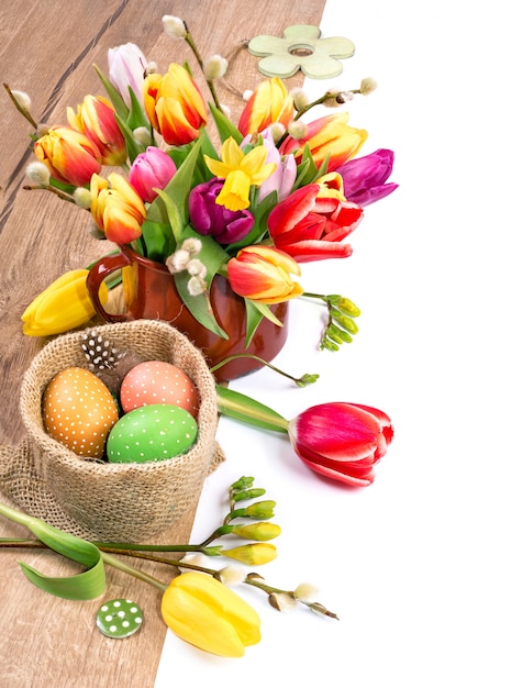 Colorful Easter border with bunch of tulips and painted eggs on wood,