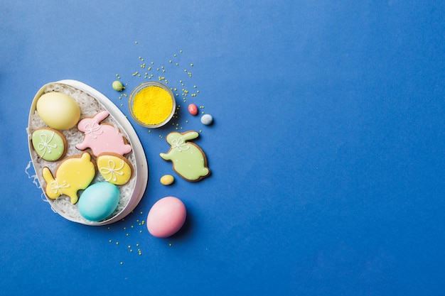 Красочные пасхальные печенья в корзине с разноцветными пасхальными яйцами на цветном фоне Пастельные цвета Пасхальные яйца концепция праздника с копией пространства