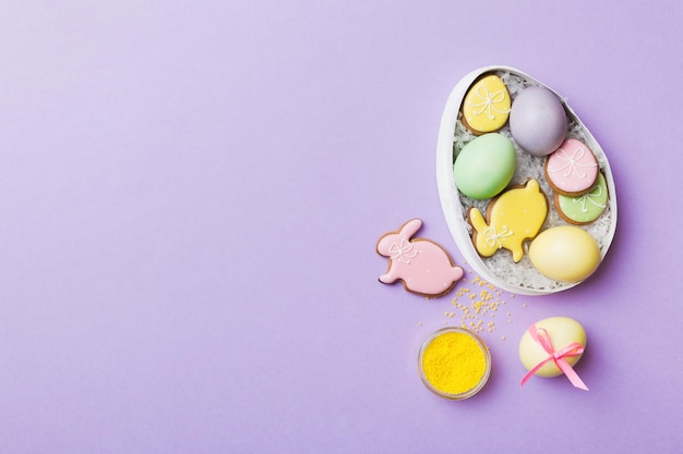 Colorful easter cookies in basket with Multi colors Easter eggs on colored background Pastel color Easter eggs holiday concept with copy space