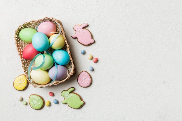 Colorful easter cookies in basket with Multi colors Easter eggs on colored background Pastel color Easter eggs holiday concept with copy space