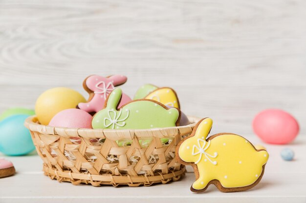 Colorful easter cookies in basket with Multi colors Easter eggs on colored background Pastel color Easter eggs holiday concept with copy space