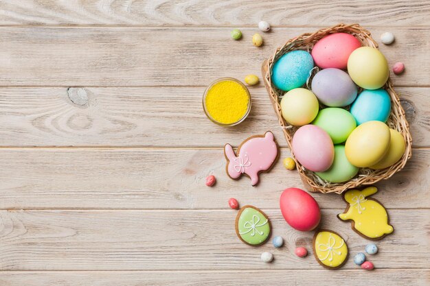 Colorful easter cookies in basket with Multi colors Easter eggs on colored background Pastel color Easter eggs holiday concept with copy space