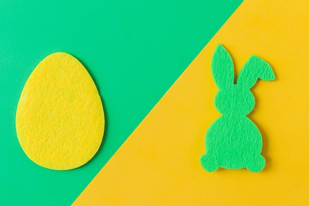 Colorful Easter egg and bunny on green and yellow background flat lay space for text Happy Easter