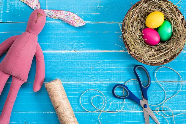 Colorful easter egg in nest on blue wood board