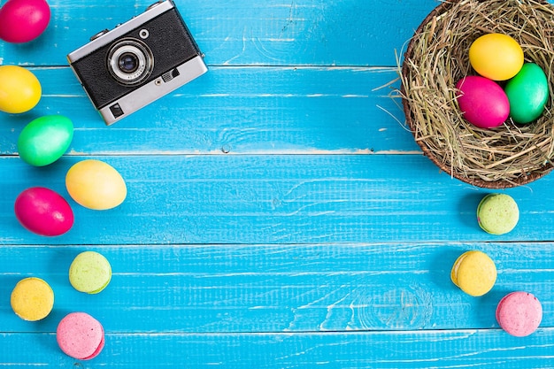 Красочное пасхальное яйцо в гнезде на синей деревянной доске