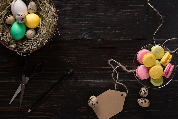 Colorful easter egg in nest on dark wood board