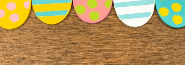 Colorful Easter eggs banner upper border, old rustic wood background, flat lay design, top view with copy space photo