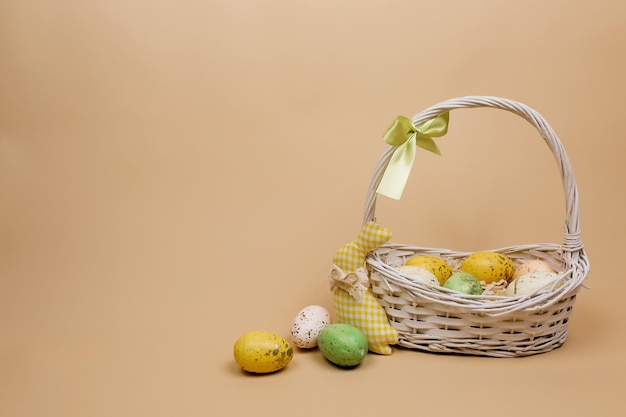 Colorful Easter eggs in a basket on a beige background