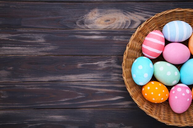 Colorful easter eggs in basket on brown wooden 