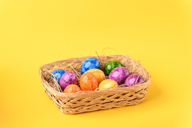 Colorful easter eggs in the basket on the yellow background