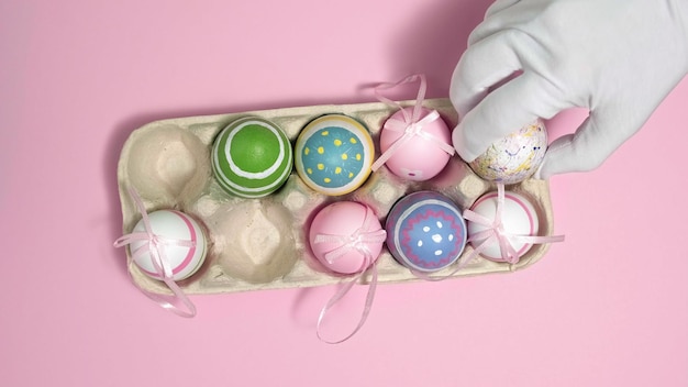 ピンクの背景の段ボール箱にカラフルなイースターの卵紙の卵のコンテナに卵ハッピーイースターのための色とりどりの卵こんにちは春とハッピーイースターの休日のコンセプト上面図