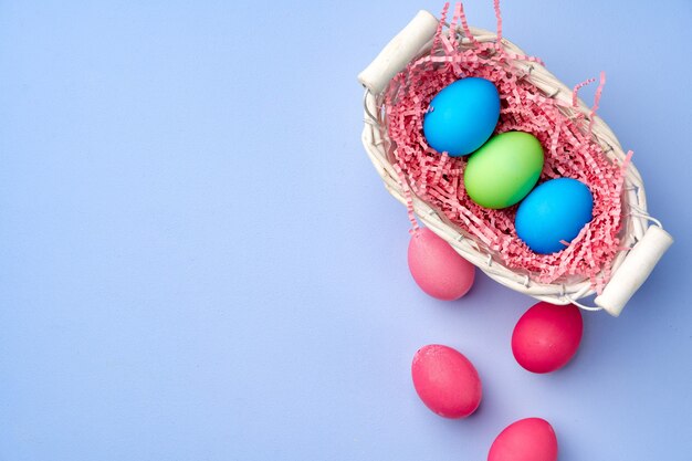 Colorful Easter eggs in decorative nest on blue