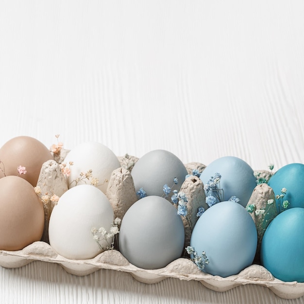 Colorful Easter eggs and flowers decor in carton pack blue beige white neutral colors festive