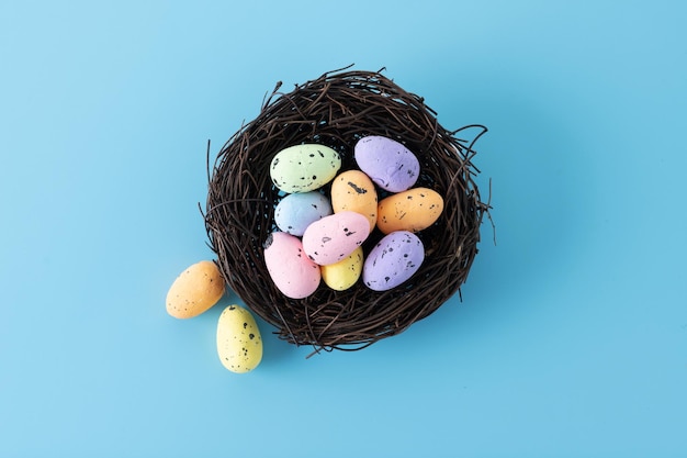 Colorful Easter eggs inside a nest on blue background