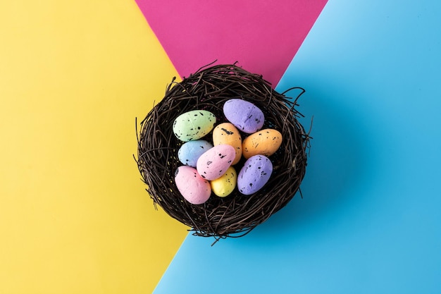 Colorful Easter eggs inside a nest on colorful background