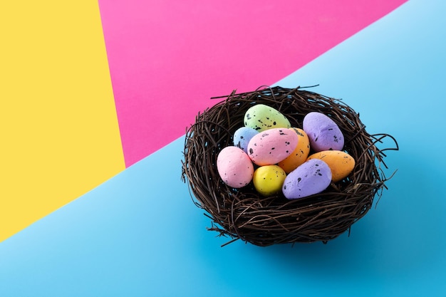 Colorful Easter eggs inside a nest on colorful background