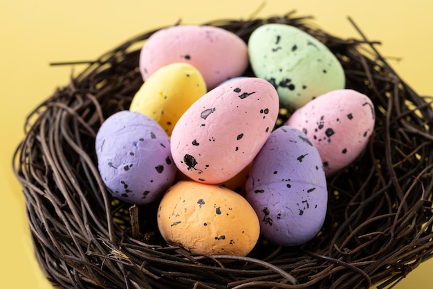 Colorful Easter eggs inside a nest on yellow background