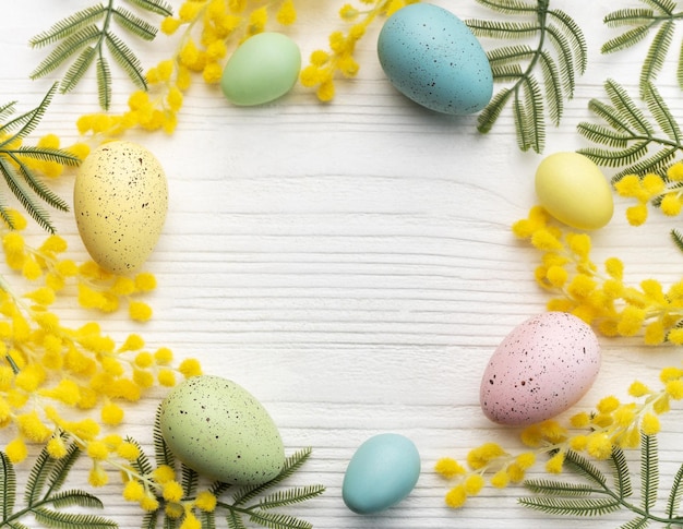 Colorful easter eggs and mimosa flowers on wooden table