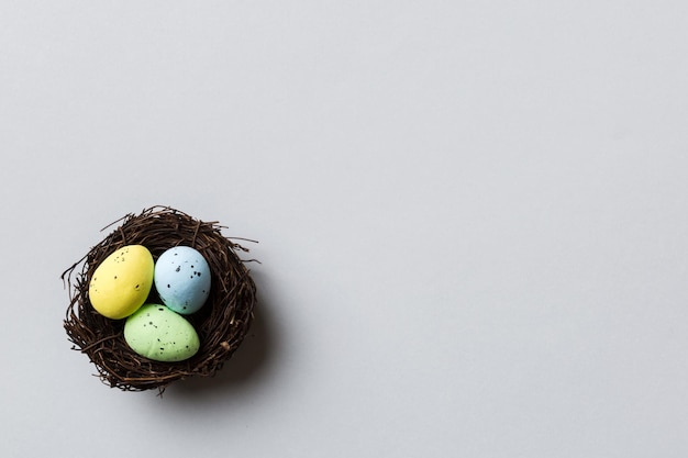 Colorful easter eggs in nest on table background with copy space top view