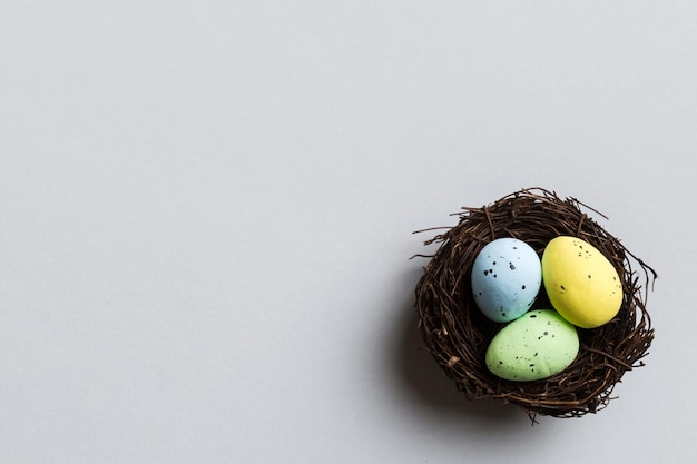 Photo colorful easter eggs in nest on table background with copy space top view