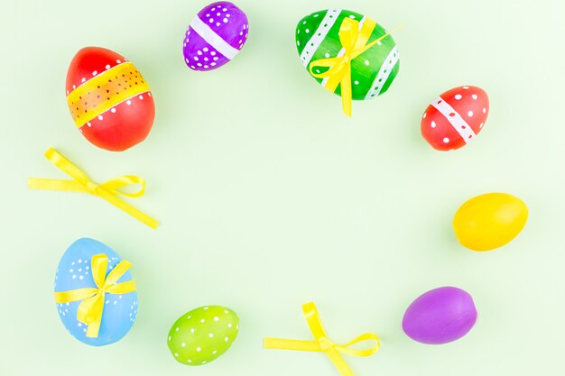 Colorful easter eggs on pastel green background flat lay. Copy space