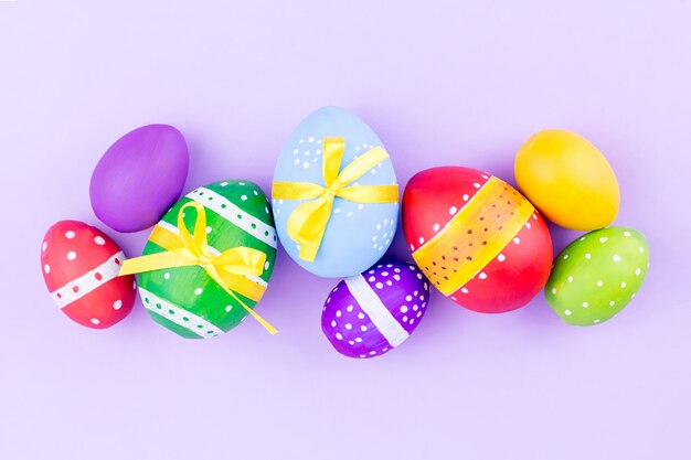 Colorful easter eggs on pastel purple background flat lay. Copy space