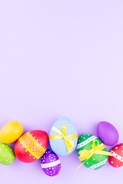 Colorful easter eggs on pastel purple background flat lay. copy space