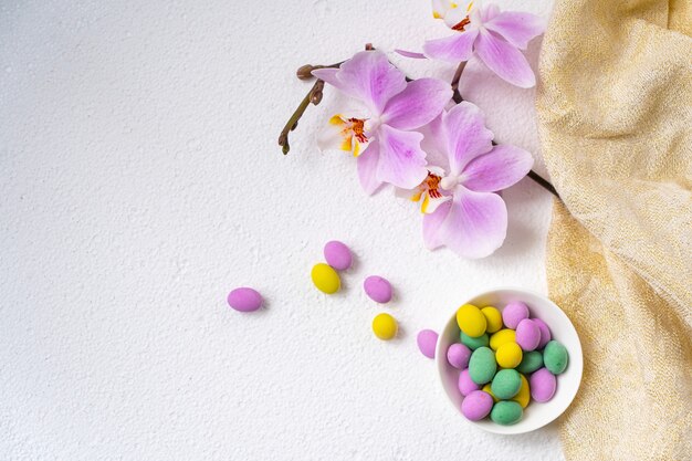 Colorful easter eggs and phalaenopsis orchid flower with plate on white desk. Top view, horisontal. Poster, mock up for design. Selective focus