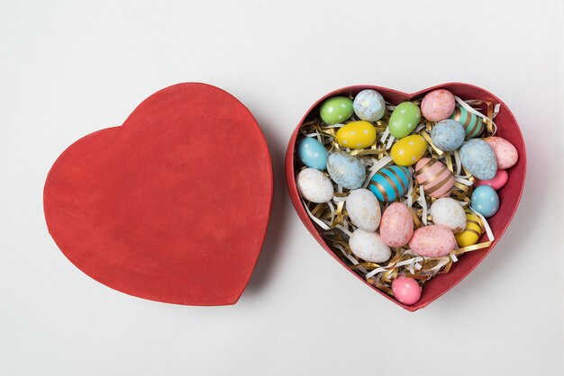Colorful Easter eggs in red heart shaped box. Gift for Easter.