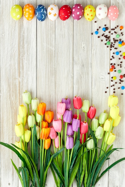 Colorful Easter eggs and tulips on wood 