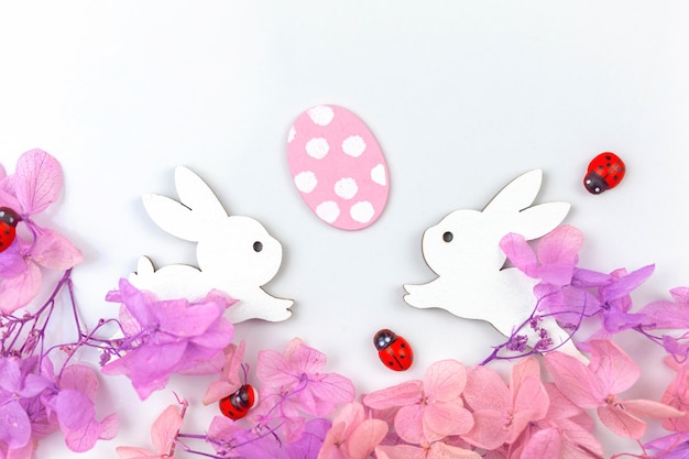 Colorful easter eggs with flowers and rabbits Border design with pink spring flowers Happy easter greetings concept holiday decoration background with copy space flat lay top view photo