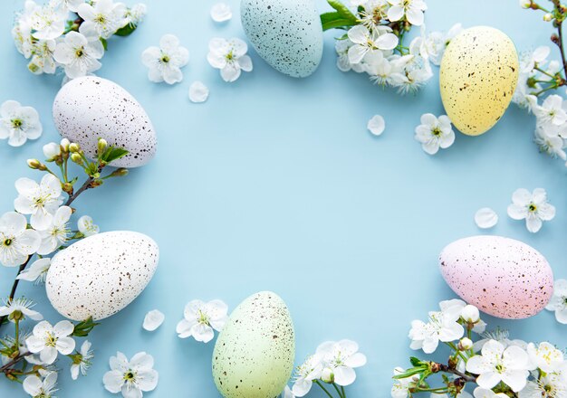 Colorful Easter eggs with spring blossom flowers over blue surface