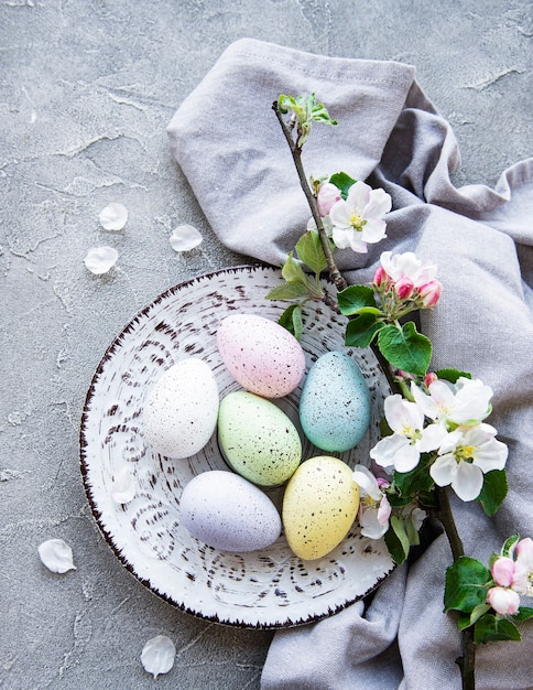 Colorful Easter eggs with spring blossom flowers over gray concrete table.