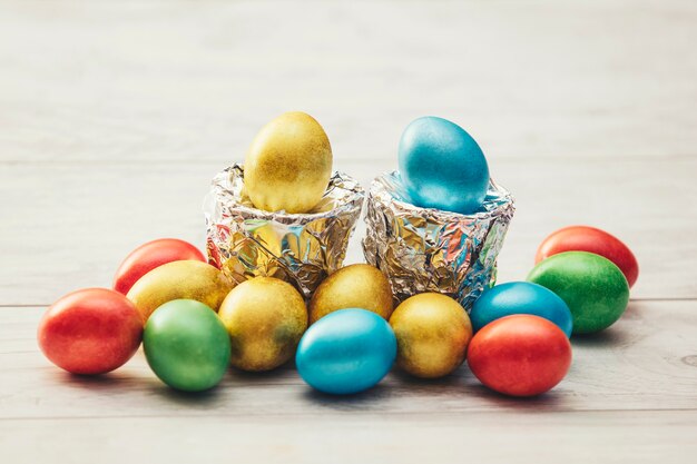 Colorful Easter eggs with stands of silver foil on a wooden table