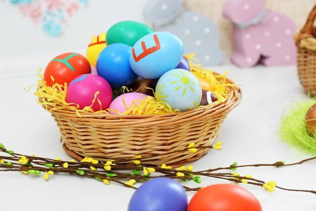 Colorful Easter eggs with willow branch on table closeup