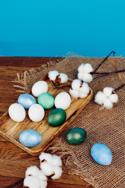 Colorful easter eggs on wooden board blue background white pussy willow flowers high quality photo