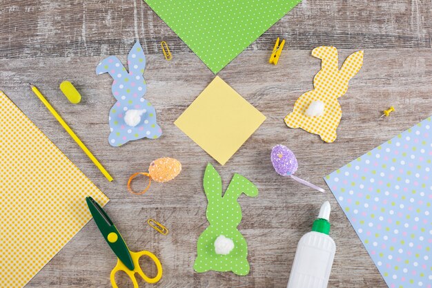 Colorful easter paper bunnys rabbits with a tail on wooden table