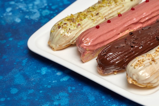 Colorful eclair cakes with cream on blue background