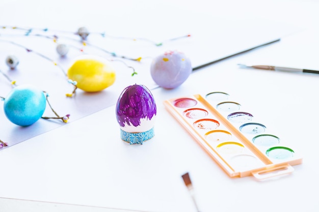 A colorful egg with a paint brush sits on a table next to a paintbrush.