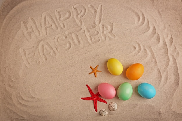 다채로운 계란과 모래에 쓰여진 텍스트 Happy Easter