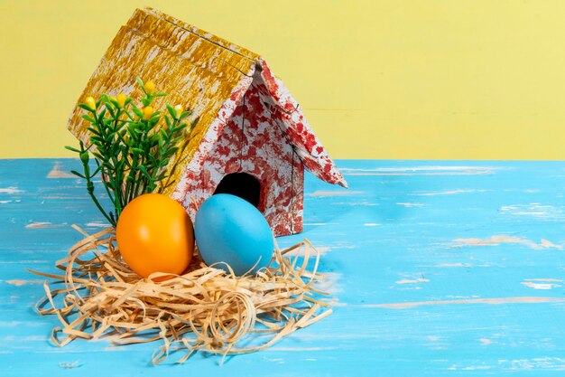 Фото Красочные яйца, символизирующие пасху, с игрушечным домом, цветами, похожими на сад.