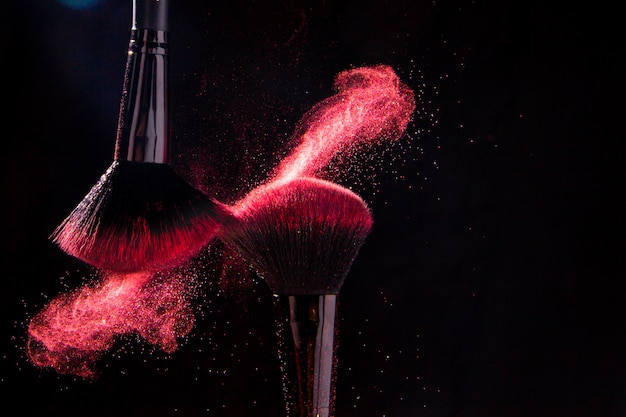 Photo colorful explosion on makeup brushes on a black background